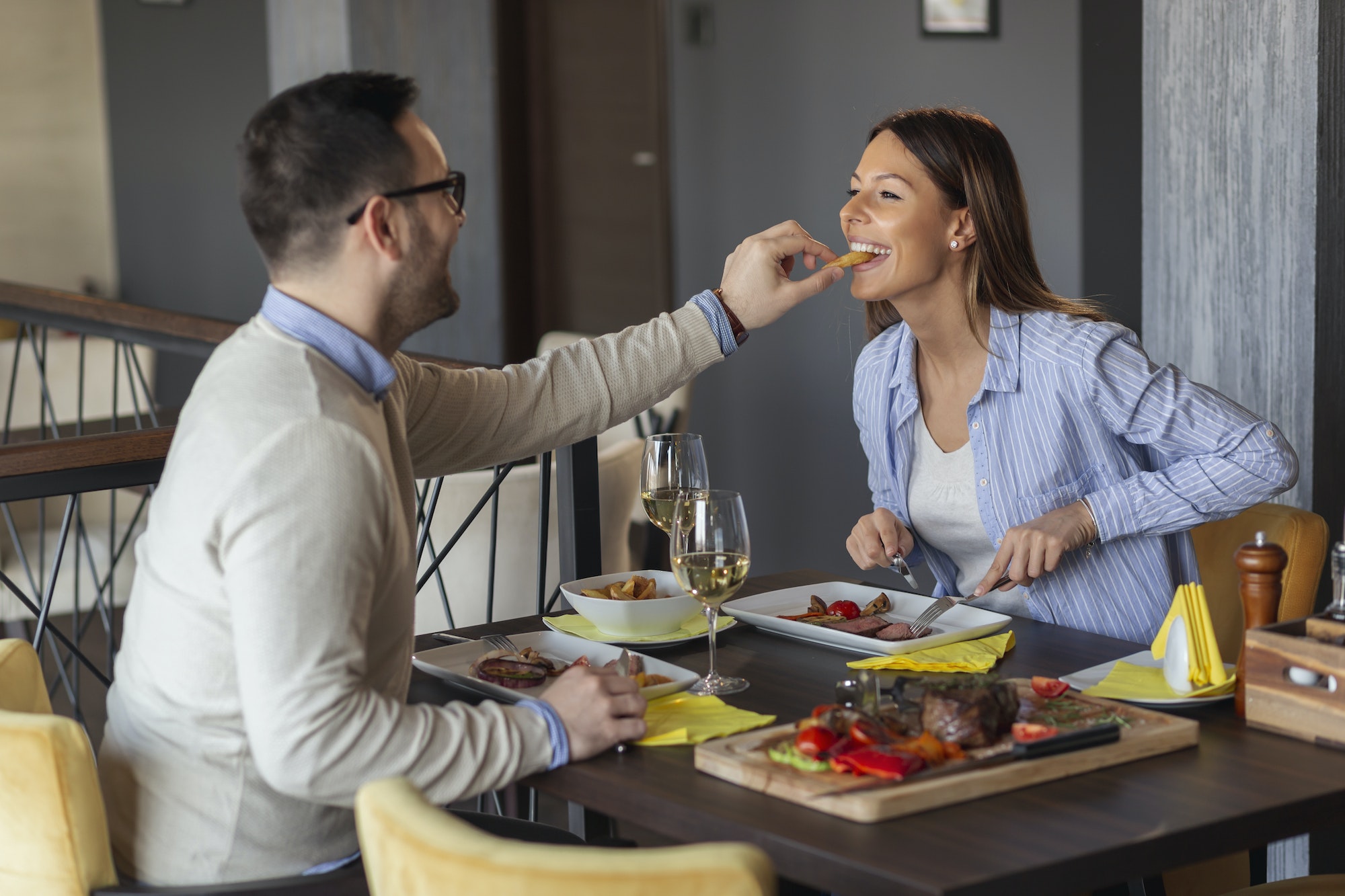 Couple tasting each other's food in restaurant