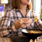 Girl eating Japanese food with chopsticks in restaurant