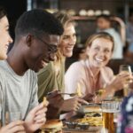 Group Of Young Friends Meeting For Drinks And Food In Restaurant