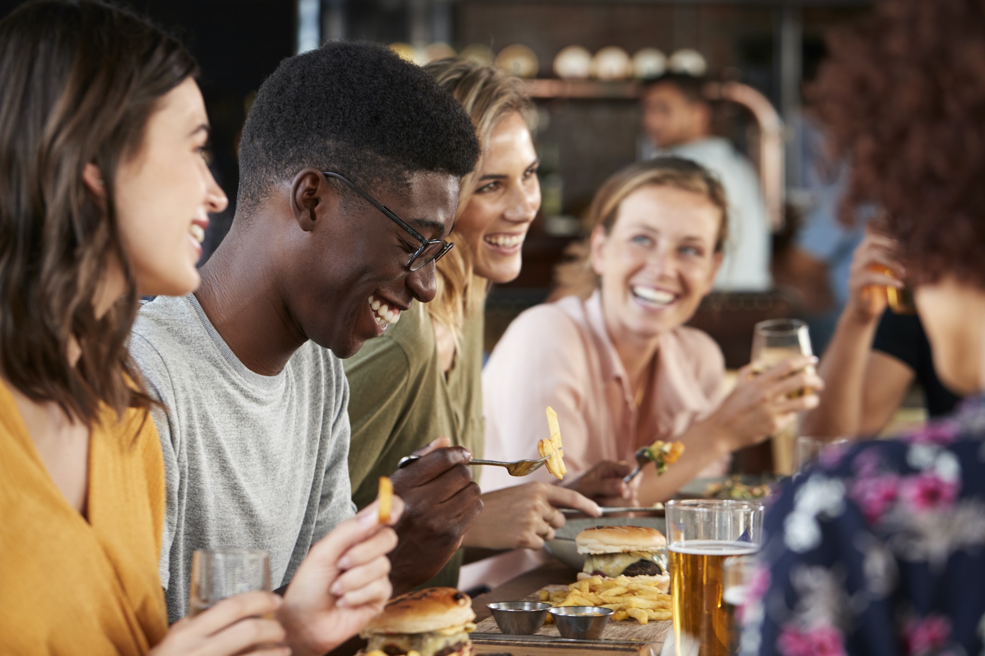 Group Of Young Friends Meeting For Drinks And Food In Restaurant